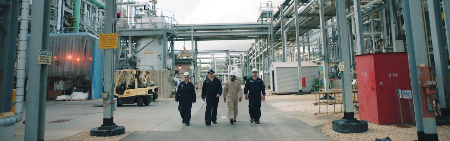 People walking towards the camera in an outdoor factory